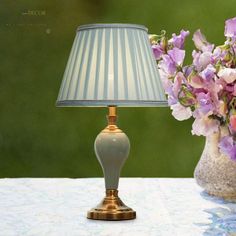 a vase with flowers and a lamp sitting on a table next to the same one