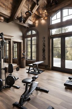 there are many exercise machines in this gym room with wood flooring and large windows