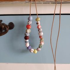 two necklaces hanging from hooks on a wall next to a door handle and coat hook