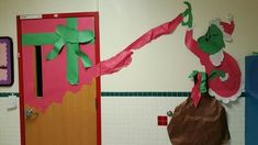 the grinch door is decorated with pink paper and green ribbon, as if it were wrapped in brown paper