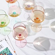 several wine glasses sitting on top of a table next to a magazine and spoons