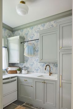 a kitchen with gray cabinets and blue wallpaper