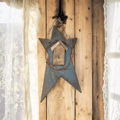 a blue star hanging on the side of a wooden wall with a birdhouse in it