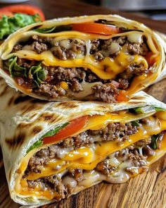 two burritos on a cutting board with lettuce, tomato and cheese