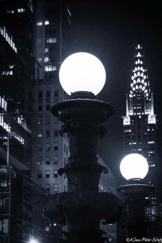 a street light in the middle of a city at night with skyscrapers behind it