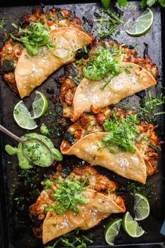 some tacos are on a tray with limes and cilantro