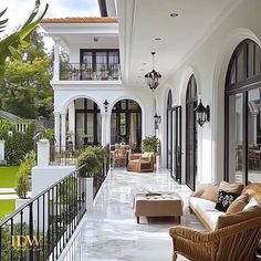 an outdoor living area with chairs, couches and tables in front of a large white house