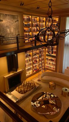 a living room filled with furniture and bookshelves next to a fire place under a chandelier