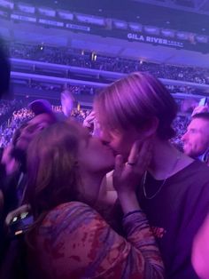 two people kissing each other at a concert