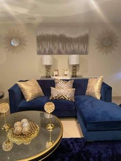 a living room filled with blue couches and gold pillows on top of each other