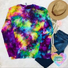 a colorful tie dye shirt, jeans and hat