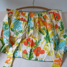 a skirt hanging on a wooden hanger with flowers and leaves all over the fabric