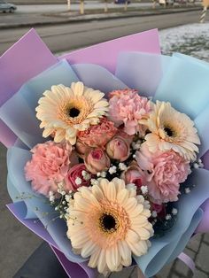 a bouquet of pink and white flowers in front of a body of water on a sidewalk