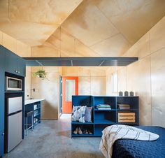 a bedroom with a bed, refrigerator and microwave in it next to a kitchen area