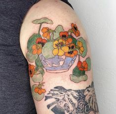 a woman's arm with flowers in a vase on it