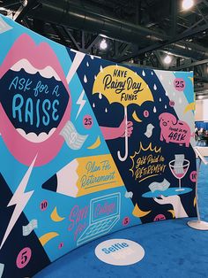 an exhibit booth with blue carpet and colorful graphics on the walls that say rise for a raise