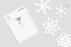 snowflakes cut out of paper and placed on top of a gray tablecloth