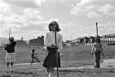 a woman holding a baseball bat while standing on top of a grass covered field next to other people