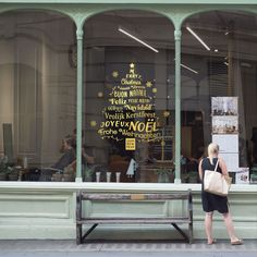 a woman standing in front of a store window with a bag on her shoulder,