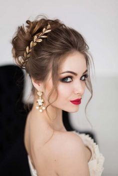 a woman with long hair wearing a white dress and gold accessories on her head is looking off to the side