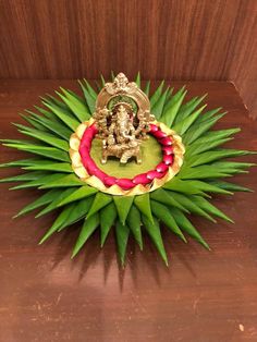 a small statue sitting on top of a lush green leafy plant next to a wooden wall