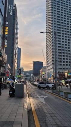 an empty city street with tall buildings in the background and people walking on the sidewalk