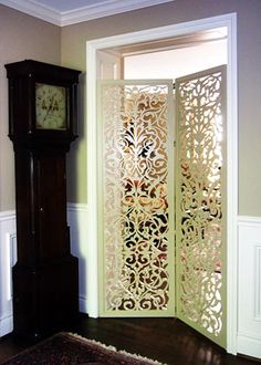 a grandfather clock sitting in the corner of a room next to an ornate screen door