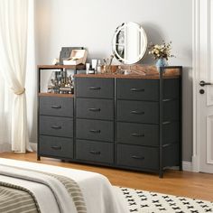 a bedroom with a bed, dresser and mirror on it's sideboard in front of a window