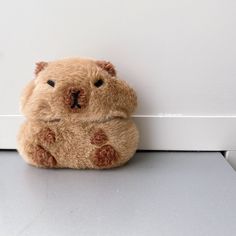 a brown teddy bear sitting next to a white wall