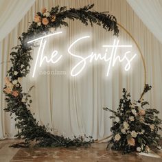 a neon sign that says the smiths with flowers on it in front of a backdrop