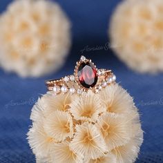 a red stone ring sitting on top of a white pom - pom ball