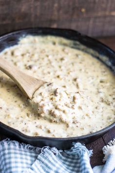 a wooden spoon in a black skillet filled with cream sauce on top of a blue and white checkered napkin