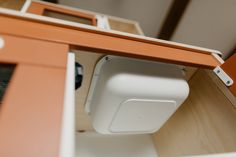 an orange and white object is sitting on the shelf in front of a mirror with its door open