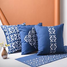 three blue pillows sitting on top of a white table