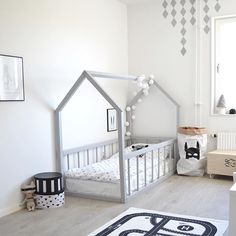 a child's bedroom decorated in white and grey with a house shaped bed frame