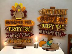 two wooden signs that say thanksgiving time and turkey trail with a lit candle in front of them