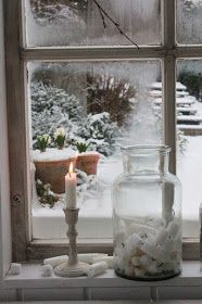 a window sill filled with candles and snow