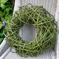 a wicker wreath sitting on top of a white chair in front of some plants