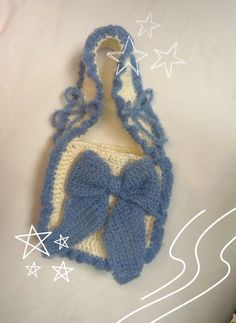 a crocheted blue and white purse with a bow on the front hanging from a hook