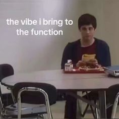 a young man sitting at a table with food in front of him