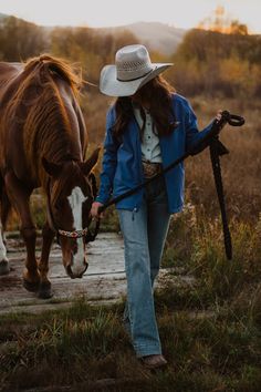 a woman is walking with her horse in the field