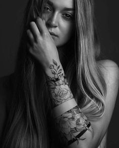 a woman with long hair and tattoos on her arm