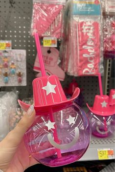 a person holding up a pink and purple cup with stars on it in a store