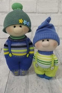 two knitted toys are standing next to each other on a white brick wall background