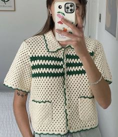 a woman taking a selfie with her cell phone in front of her face and wearing a crocheted shirt