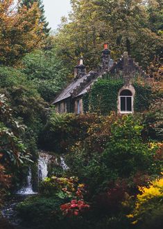 an old house in the woods with a waterfall coming out of it's window