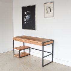 a wooden desk sitting in front of a painting on the wall next to a shelf