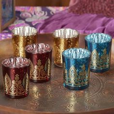 four different colored glass cups sitting on top of a wooden tray