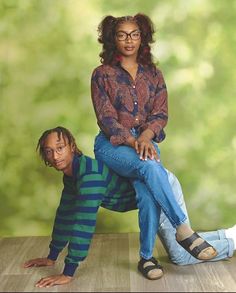 a woman sitting on top of a man's lap in front of a green background