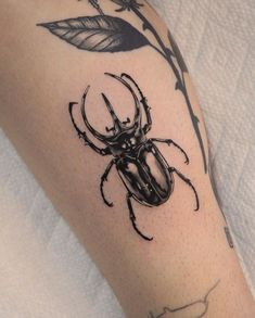 a black beetle sitting on top of a person's leg next to a flower